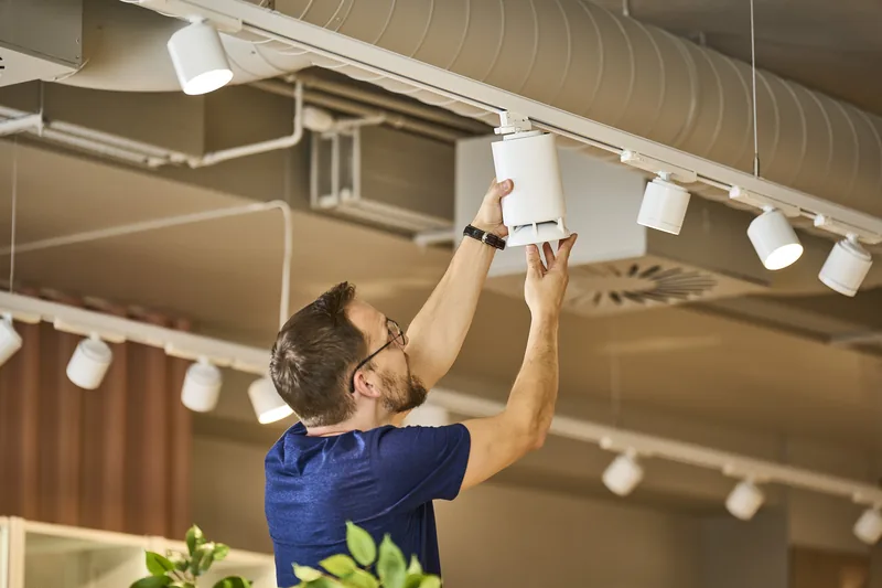 Instalador encajando un Omni Track blanco en el riel de iluminación de una tienda.