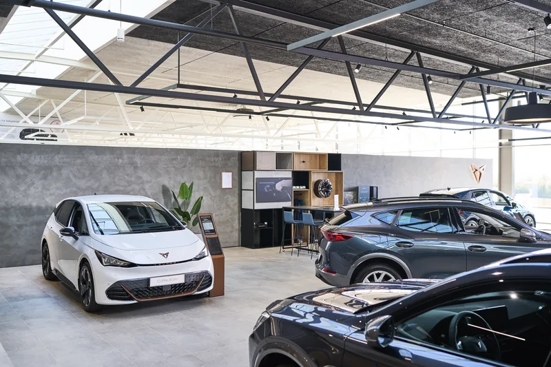 Sala de exhibición de automóviles con Omni Track en los rieles del techo y vehículos en el piso.