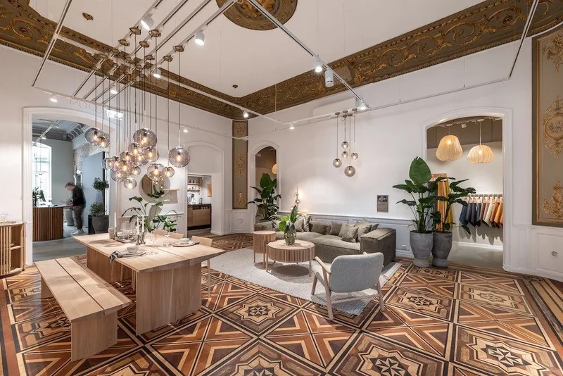 Tienda de muebles con techo de madera, piso de baldosas decoradas y lámparas colgantes.
