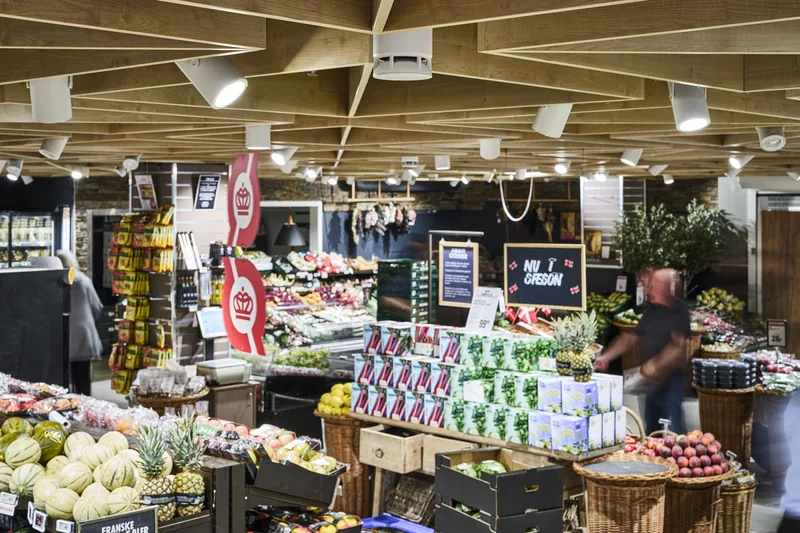 Sección de frutas y verduras de un supermercado con Omni Track blancos en los rieles del techo.